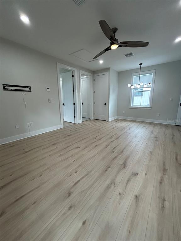 A bright room features light wood-look flooring, a ceiling fan, and a modern light fixture — 468 44TH AVENUE N UNIT 1/2, ST PETERSBURG, FL