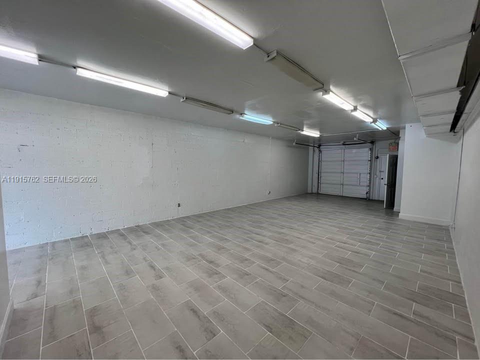 An empty commercial space features white painted block walls, gray tile flooring, and overhead lighting — 1812 N Dixie Hwy, Hollywood FL 33020, HOLLYWOOD, FL