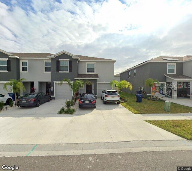 A street-level view shows a row of modern two-story townhouses with attached garages and driveways — 2908 EVERGREEN ELM PASS, WESLEY CHAPEL, FL