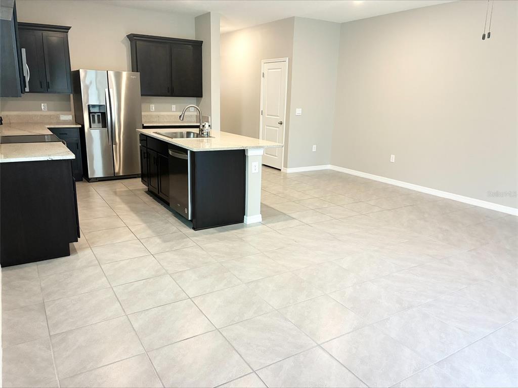 A kitchen with dark cabinets, stainless steel appliances, and a granite-topped island on tile flooring — 2908 EVERGREEN ELM PASS, WESLEY CHAPEL, FL