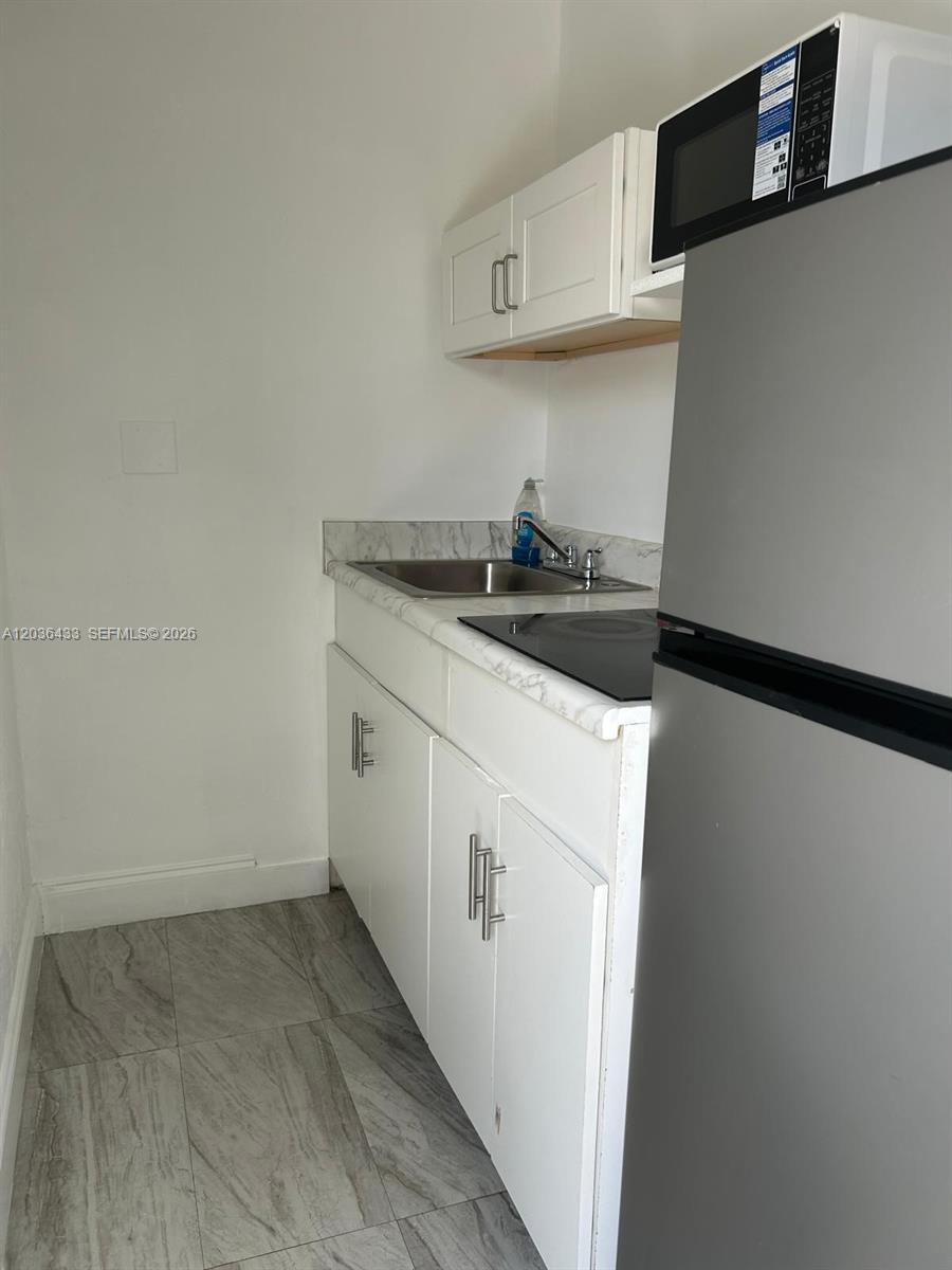 A small kitchen features white cabinets, a stainless steel sink, and a stainless steel refrigerator — 16271 SW 92nd Ter # 0, Miami FL 33196, MIAMI, FL