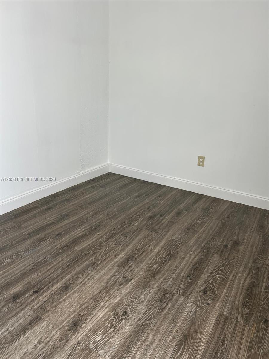 An empty room features white walls, white baseboards, and dark wood-look laminate flooring — 16271 SW 92nd Ter # 0, Miami FL 33196, MIAMI, FL