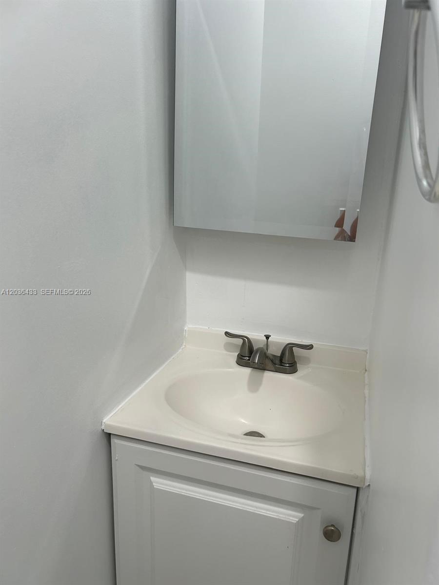 A small bathroom features a white vanity cabinet, a sink, and a wall-mounted mirror — 16271 SW 92nd Ter # 0, Miami FL 33196, MIAMI, FL