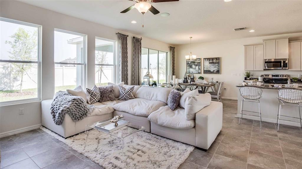 An open-concept kitchen and living area featuring white cabinets, a kitchen island, and wood-look flooring — 5432 SILVER MOONLIGHT DRIVE, PALMETTO, FL