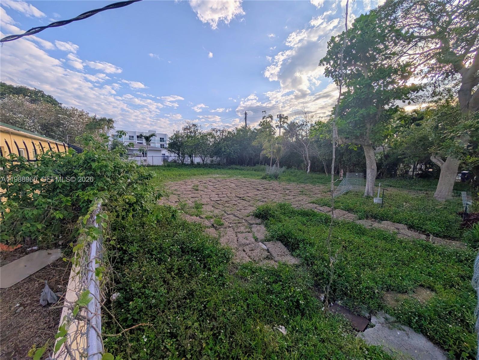 An outdoor view of a vacant, grassy lot with scattered patches of sod and trees — 660 NE 86th St, Miami FL 33138, MIAMI, FL