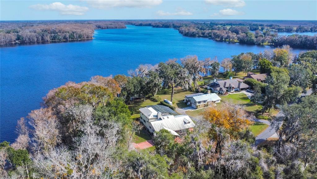 An aerial view shows houses nestled among trees along the shore of a large lake — 6121 S SUNWAY POINT, FLORAL CITY, FL