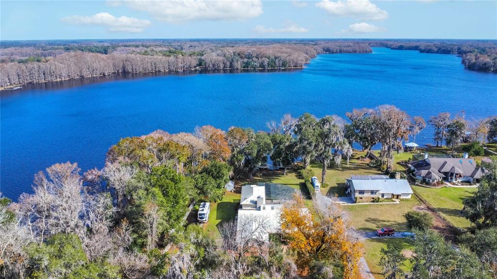 An aerial view shows two houses situated on a grassy lot beside a large lake — 6121 S SUNWAY POINT, FLORAL CITY, FL