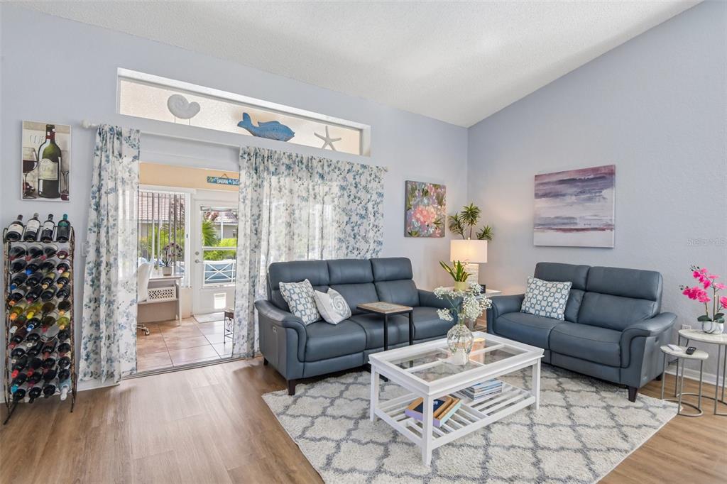 A living room features two blue leather sofas, a glass-topped coffee table, and sliding glass doors — 9330 NEW ORLEANS DRIVE, WEEKI WACHEE, FL