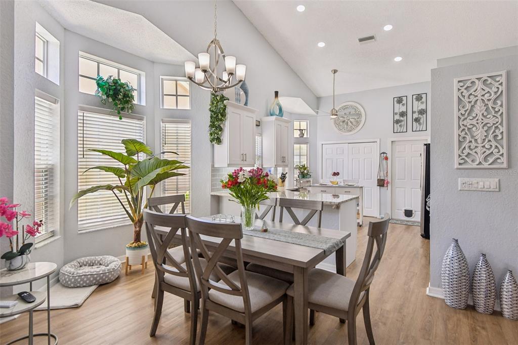 A dining area with a wooden table, chairs, and a kitchen island under vaulted ceilings — 9330 NEW ORLEANS DRIVE, WEEKI WACHEE, FL