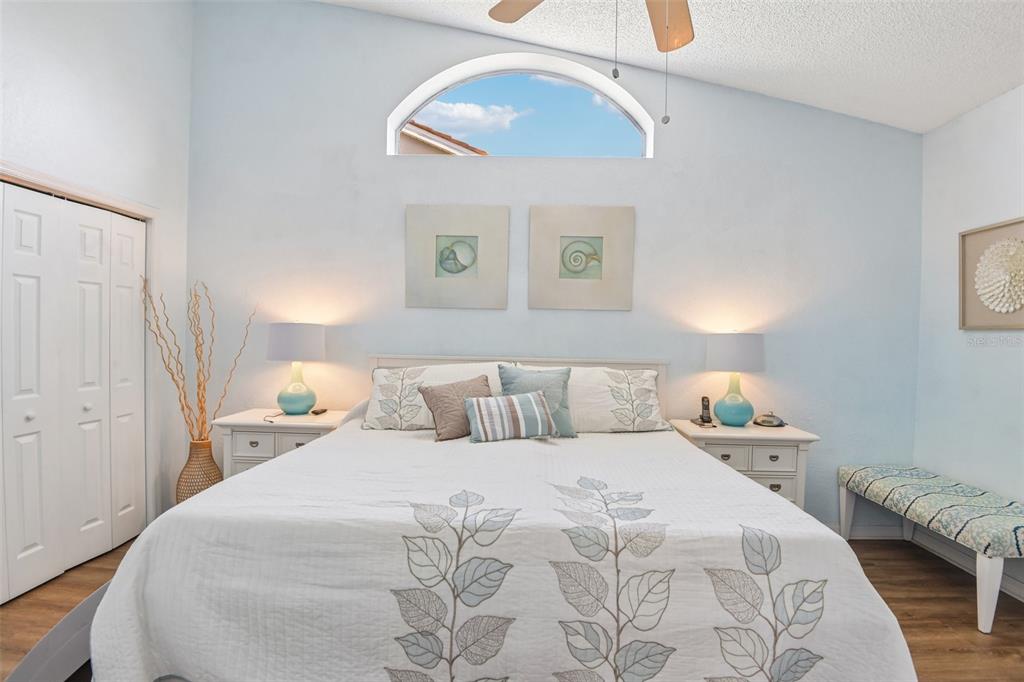 A bedroom features a bed with a leaf-patterned quilt, two nightstands, and an arched window — 9330 NEW ORLEANS DRIVE, WEEKI WACHEE, FL