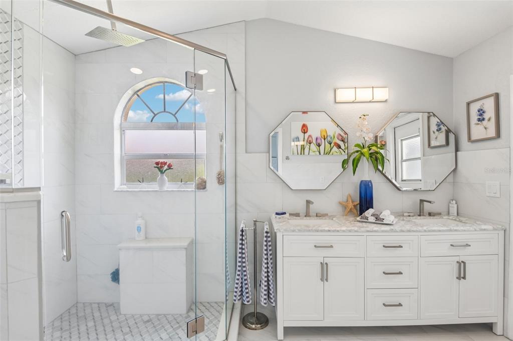 A bathroom features a glass-enclosed shower, a double vanity with mirrors, and white tile walls — 9330 NEW ORLEANS DRIVE, WEEKI WACHEE, FL