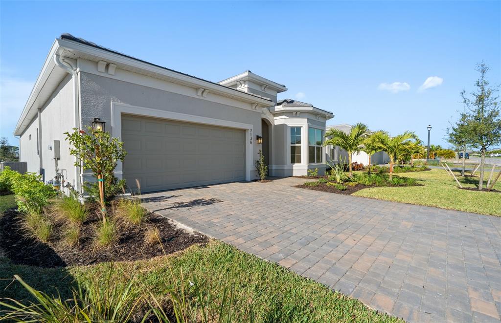 A single-story house with a beige stucco exterior, a two-car garage, and a paver driveway — 7621 FULHAM AVENUE, BRADENTON, FL