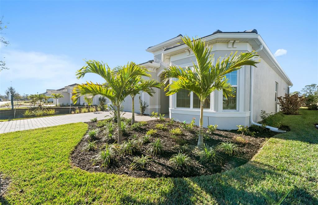 A light-colored house exterior features a landscaped front garden with two small palm trees — 7621 FULHAM AVENUE, BRADENTON, FL