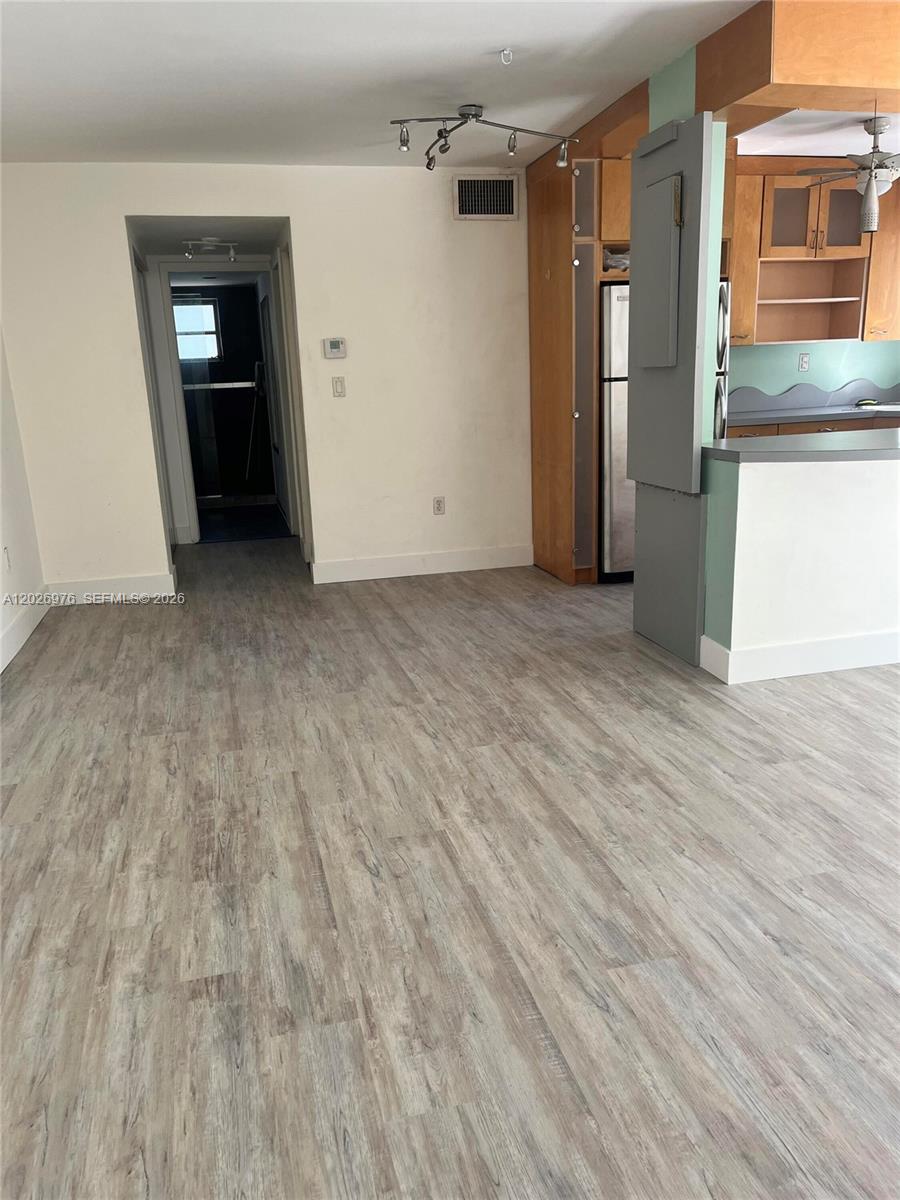 This room features light wood-look flooring, a kitchen with wooden cabinets, and a hallway entrance — 240 Collins Ave # 2B, Miami Beach FL 33139, MIAMI BEACH, FL