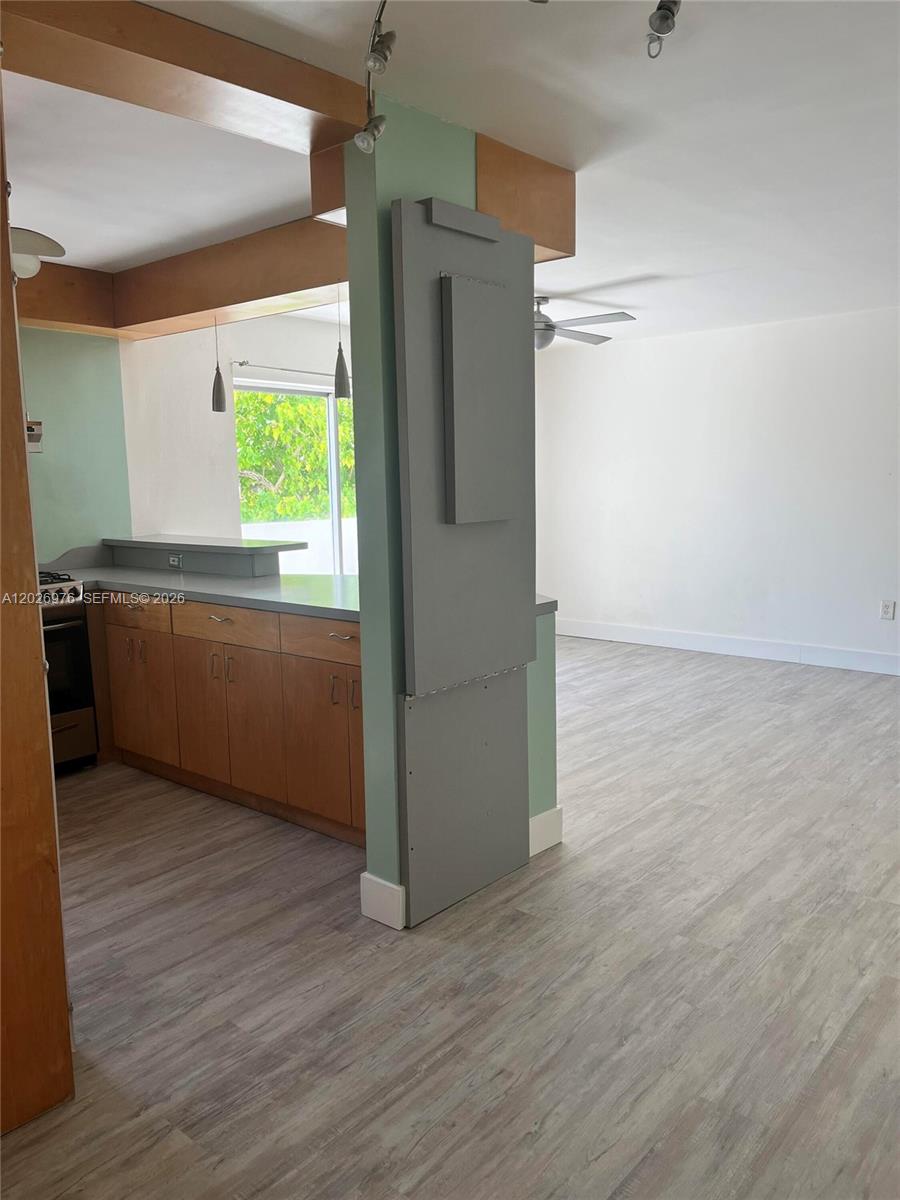A kitchen with wood cabinets and a gray partition wall opens to a living area — 240 Collins Ave # 2B, Miami Beach FL 33139, MIAMI BEACH, FL