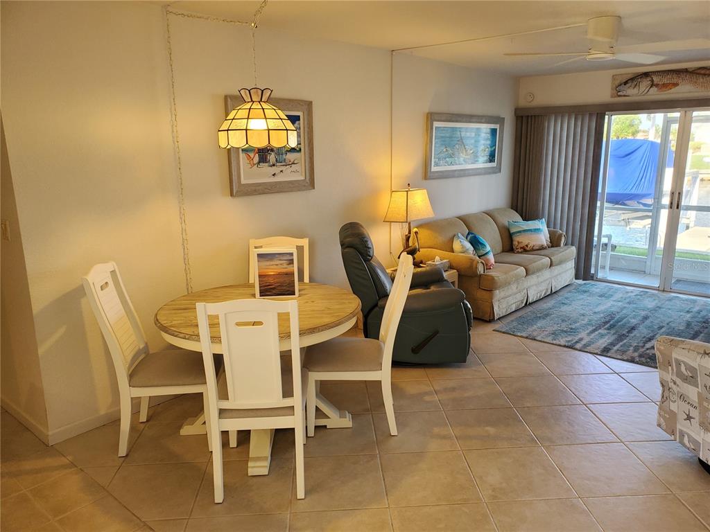 A dining area with a round table and chairs sits adjacent to a living room — 311 GARVIN STREET UNIT 407A, PUNTA GORDA, FL