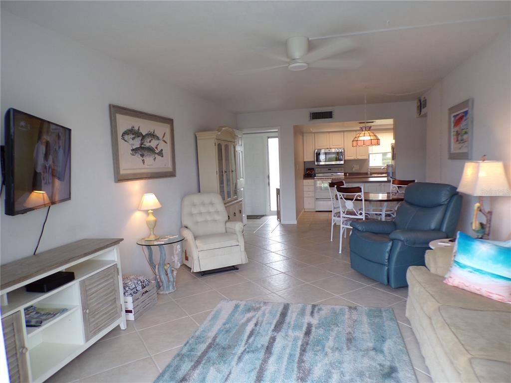 A living room with tile floors, a television, and an open kitchen in the background — 311 GARVIN STREET UNIT 407A, PUNTA GORDA, FL