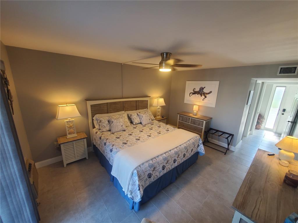 A bedroom features a king bed, two nightstands, a dresser, and tile flooring — 311 GARVIN STREET UNIT 407A, PUNTA GORDA, FL