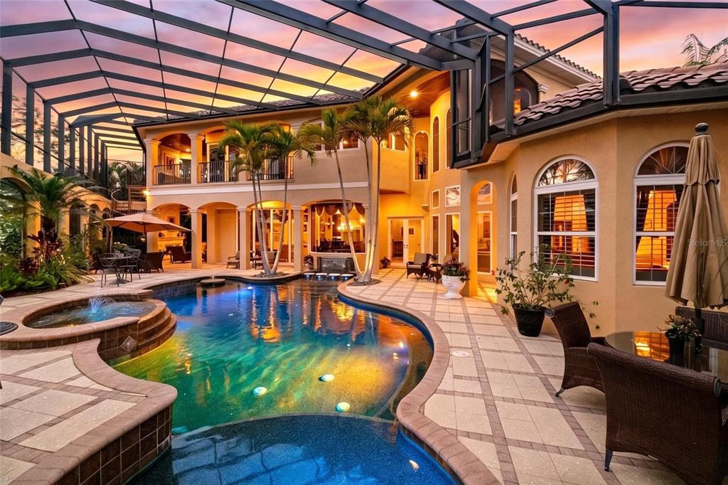 A two-story house with a screened-in pool, hot tub, and patio at sunset — 7202 TEAL CREEK GLEN, LAKEWOOD RANCH, FL