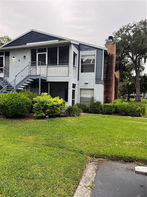 A two-story apartment building features a brick chimney, screened balconies, and an exterior staircase — 408 NORTHLAKE DRIVE UNIT 0, SANFORD, FL