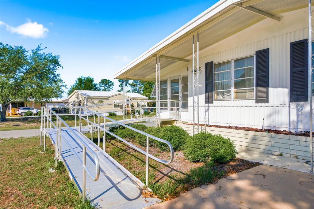 A mobile home exterior features a metal wheelchair ramp leading to the front entrance — 7557 FAIRLANE AVENUE, BROOKSVILLE, FL