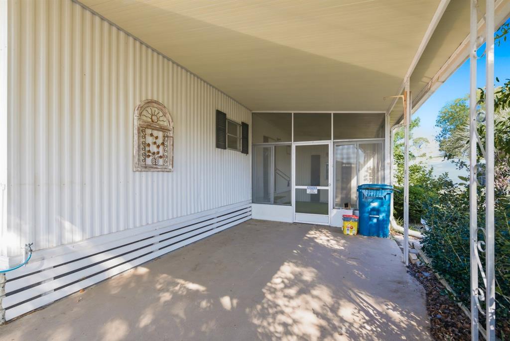 A covered concrete patio leads to a screened-in entryway of a mobile home — 7557 FAIRLANE AVENUE, BROOKSVILLE, FL