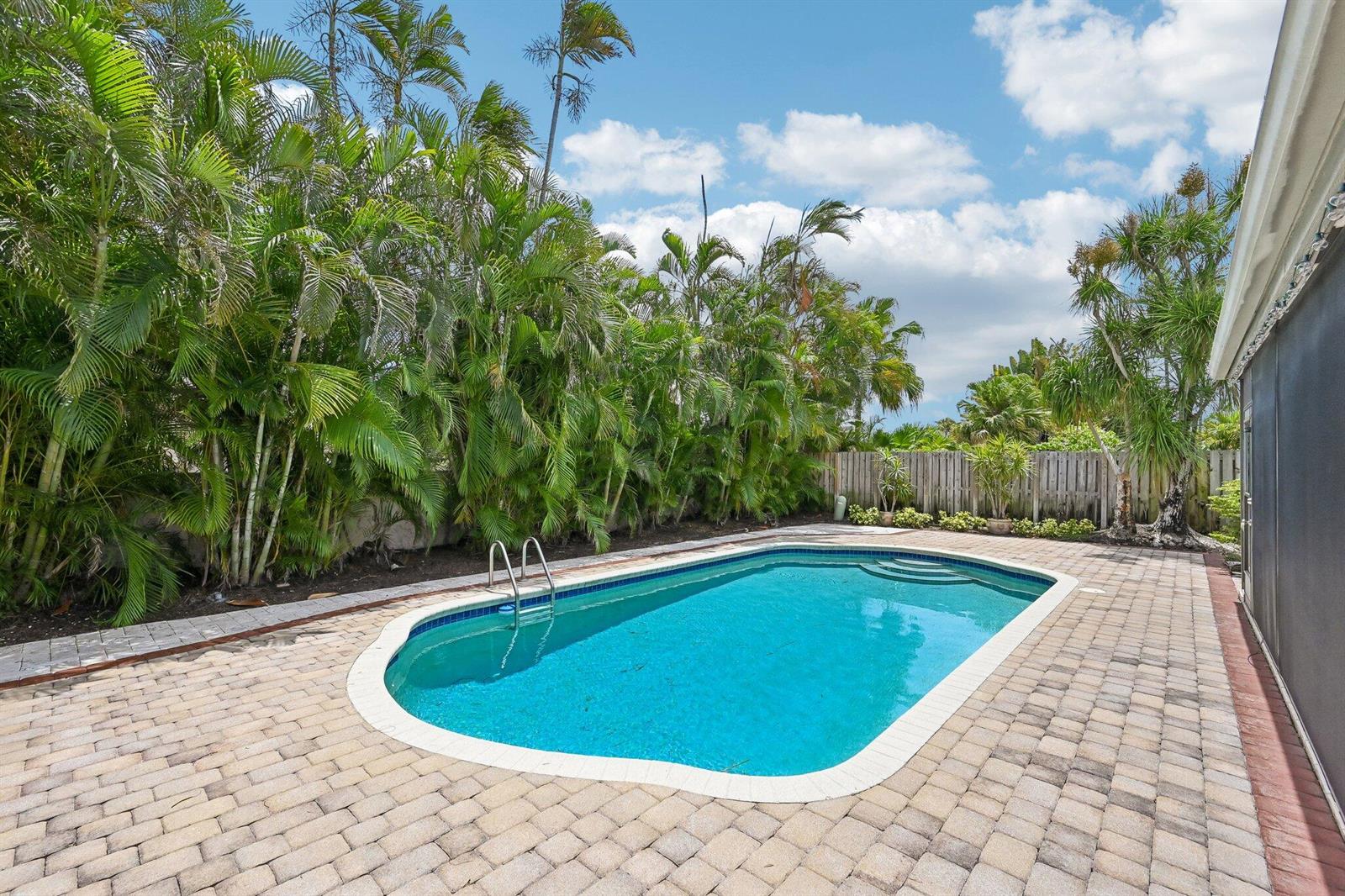 A backyard swimming pool surrounded by a paver patio, palm trees, and a wooden fence — 1232 NW 14th Street, Boca Raton FL 33486, BOCA RATON, FL