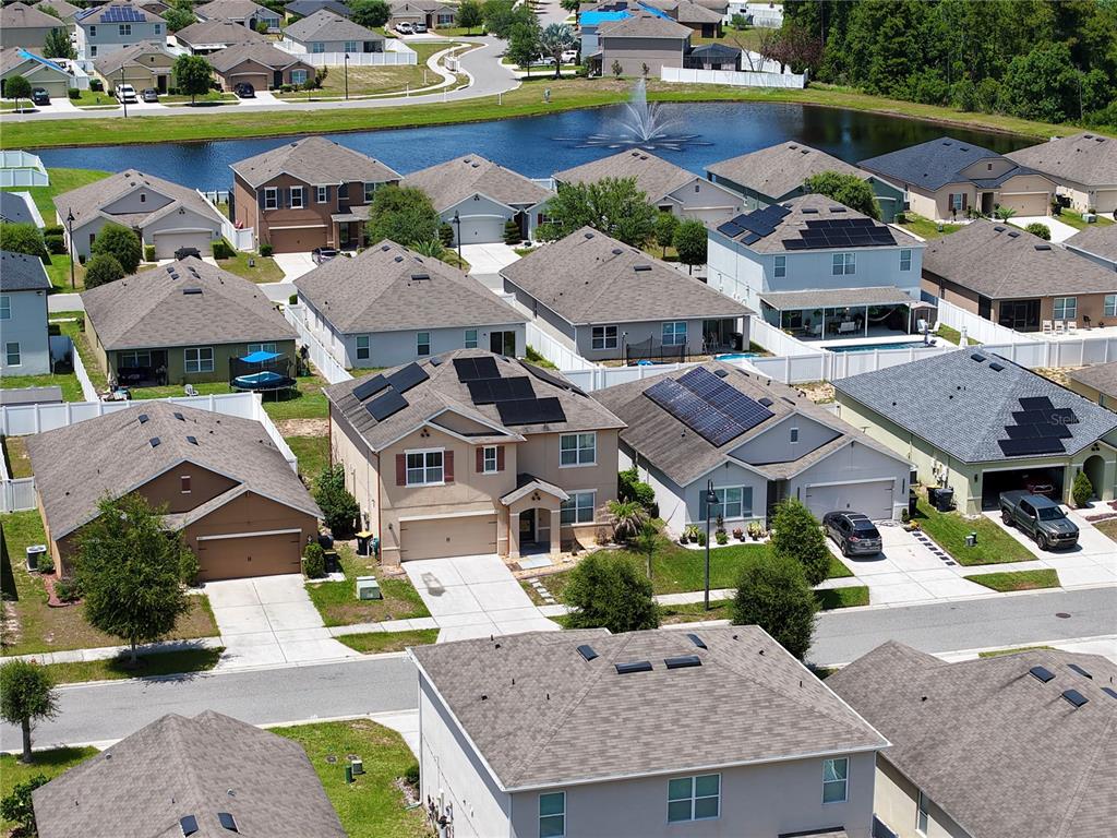 An aerial view shows a suburban neighborhood with houses, a pond, and a fountain — 401 BRIAR PATCH LOOP, DAVENPORT, FL
