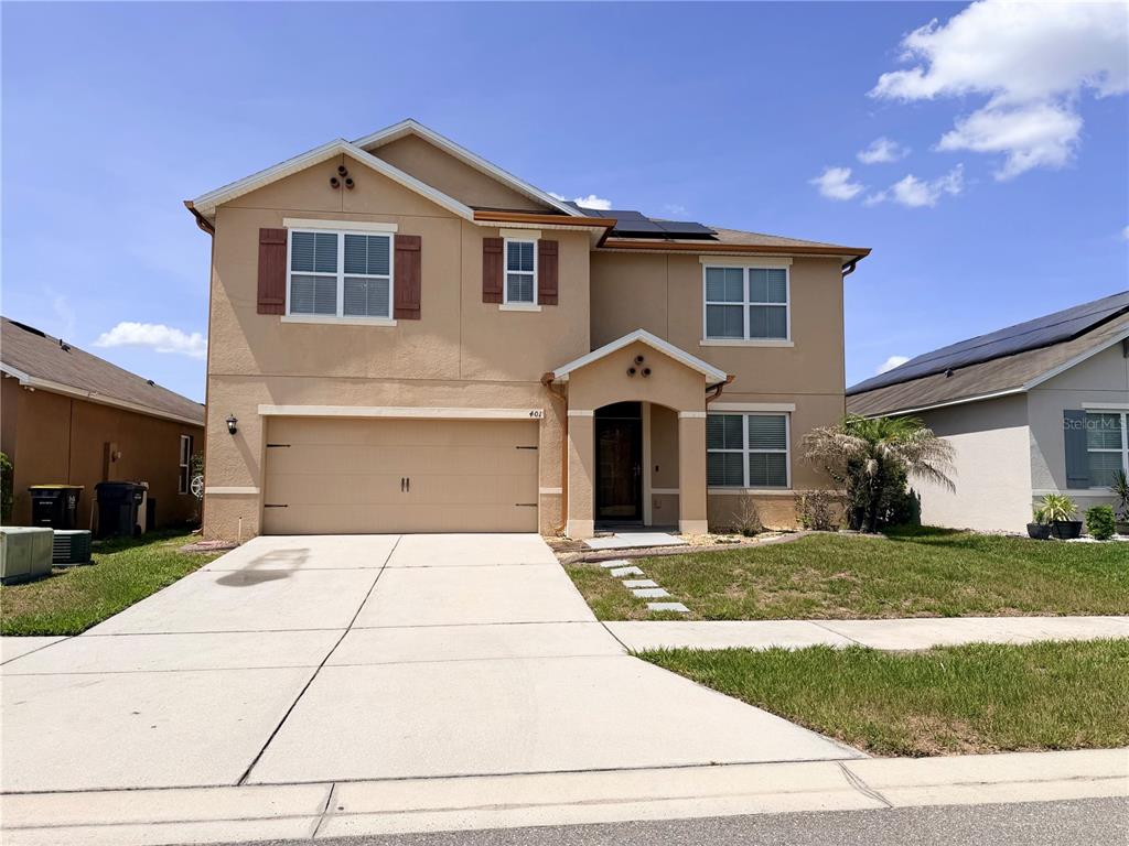 A two-story tan stucco house with a two-car garage and a front porch — 401 BRIAR PATCH LOOP, DAVENPORT, FL
