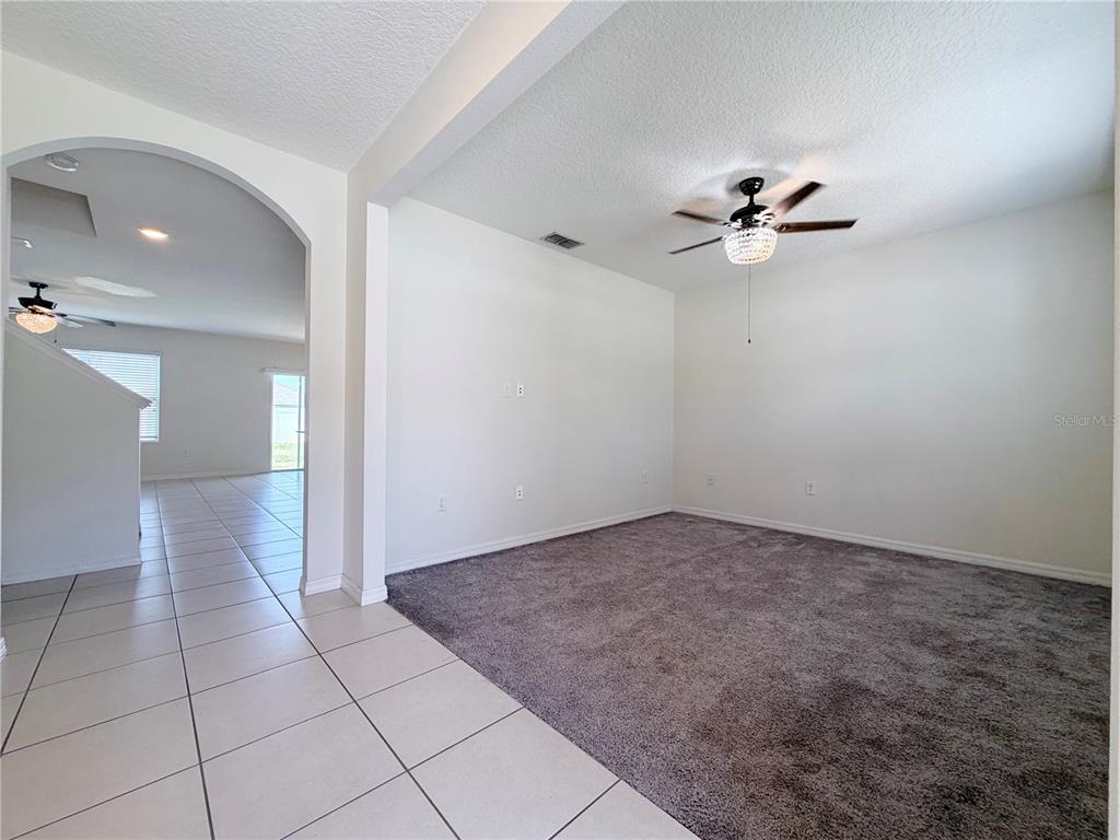 A room with gray carpeting and a ceiling fan connects to a tiled hallway — 401 BRIAR PATCH LOOP, DAVENPORT, FL