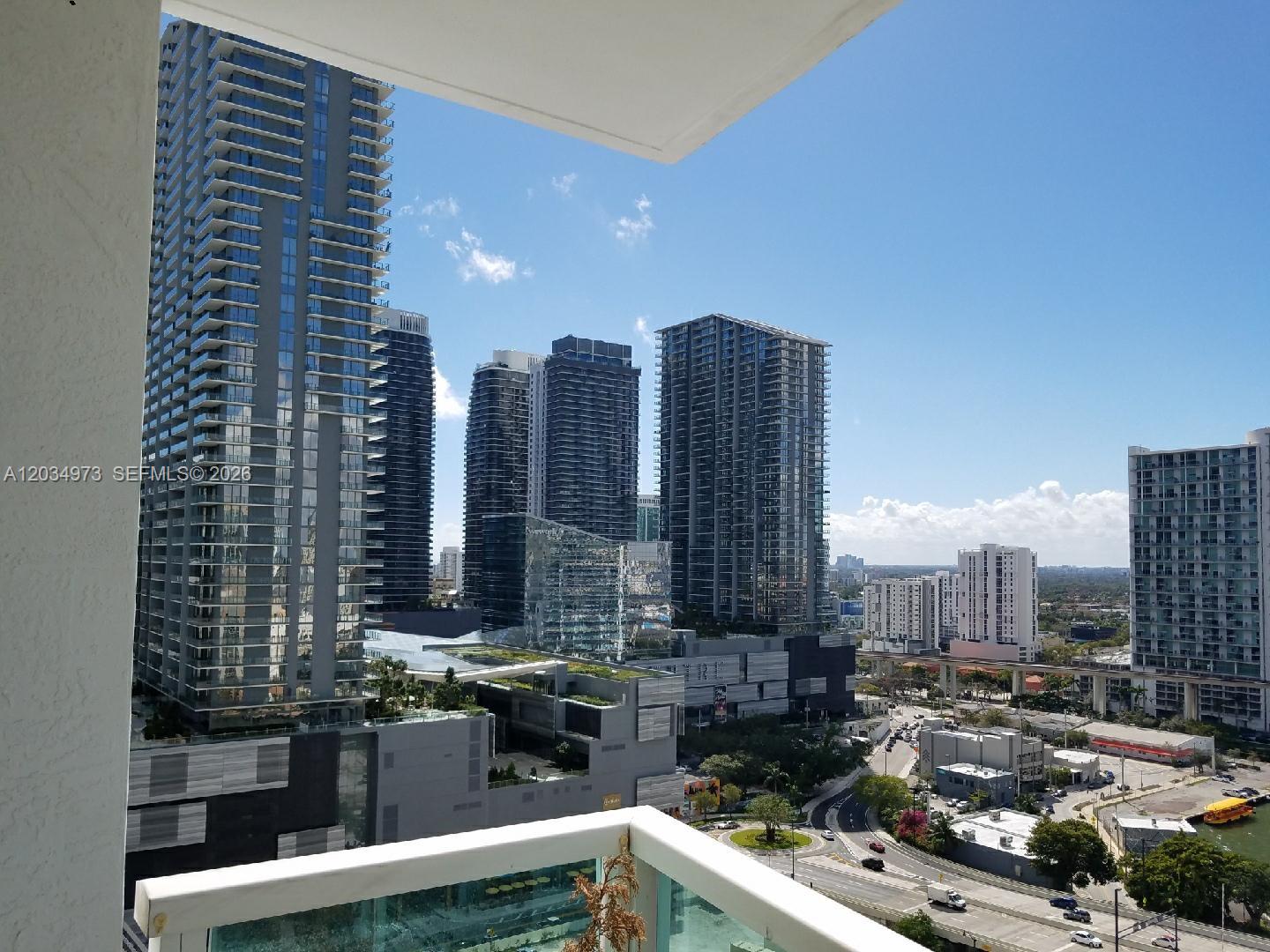 A balcony view overlooks a city skyline with several high-rise apartment buildings and a highway — 31 SE 5th St # 2205, Miami FL 33131, MIAMI, FL