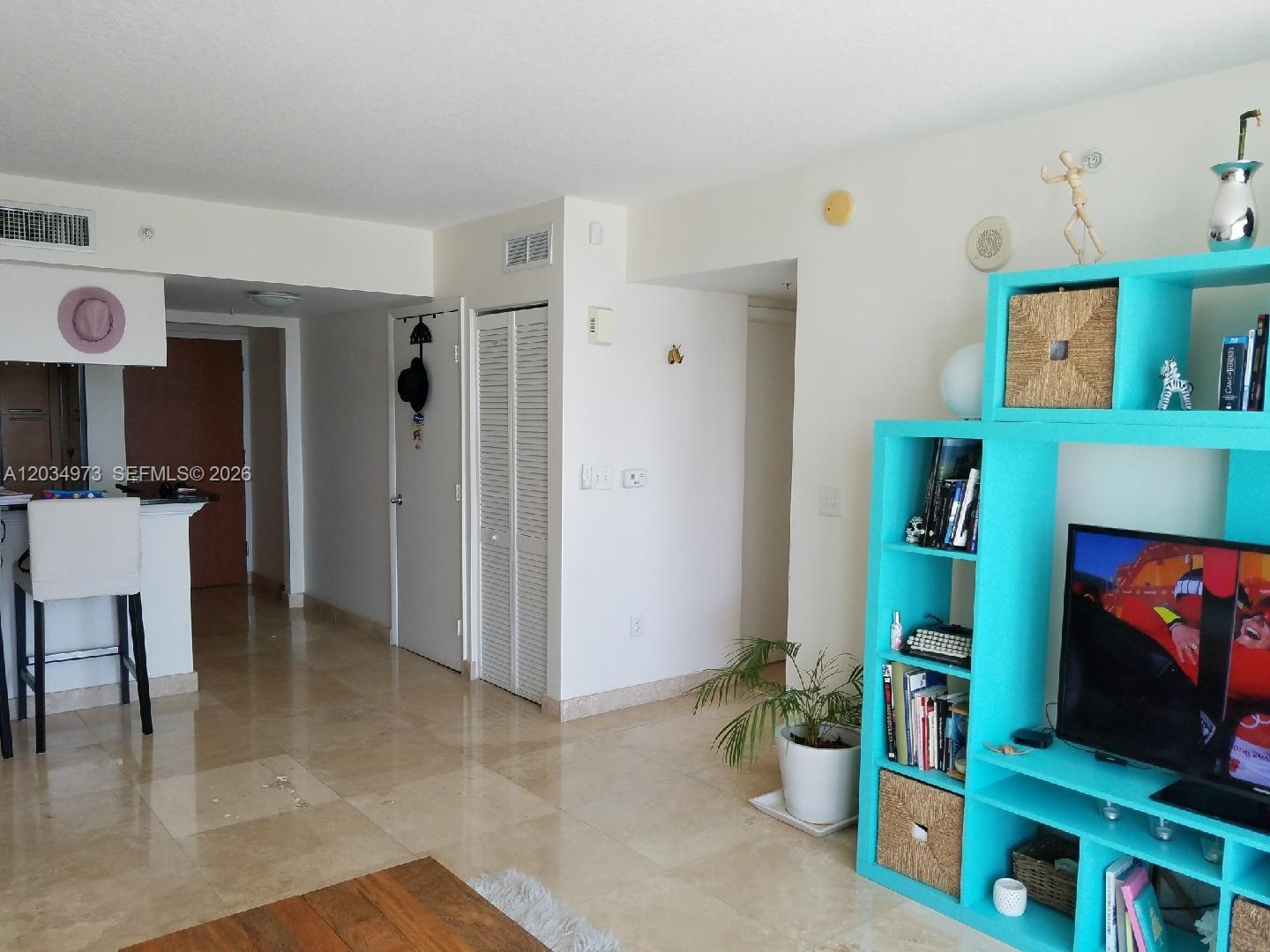 A living room features light tile floors, a bright blue shelving unit, and a kitchen counter — 31 SE 5th St # 2205, Miami FL 33131, MIAMI, FL