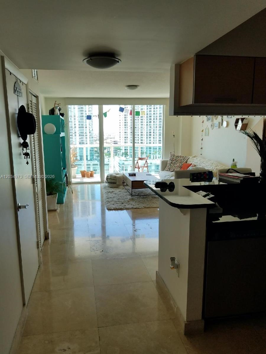 A living room with tile floors, a balcony, and a view of city buildings — 31 SE 5th St # 2205, Miami FL 33131, MIAMI, FL