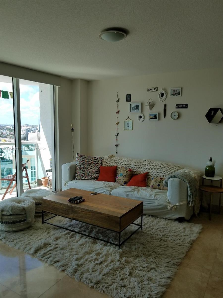 A living room features a white sofa, a wooden coffee table, and a gallery wall — 31 SE 5th St # 2205, Miami FL 33131, MIAMI, FL