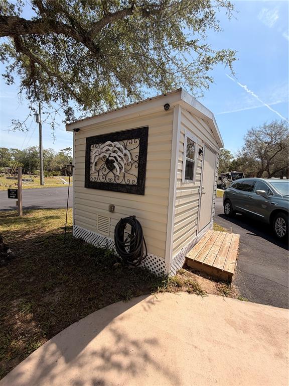 A small, light-colored storage shed with a decorative wall hanging sits on a paved lot — N SUNCOAST BOULEVARD, CRYSTAL RIVER, FL