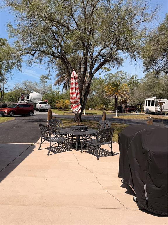 A patio with a metal table, chairs, and umbrella sits under a large tree — N SUNCOAST BOULEVARD, CRYSTAL RIVER, FL