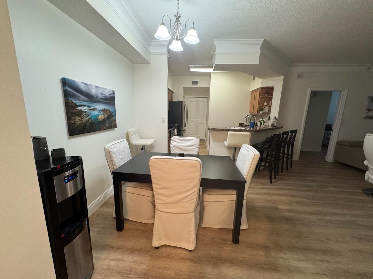 A dining area with a black table, white slipcovered chairs, and an adjacent kitchen counter — 9873 Baywinds Boulevard # 5203, West Palm Beach FL 33411, WEST PALM BEACH, FL