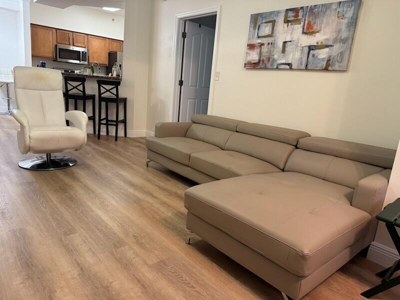 A living room features a beige sectional sofa, a white recliner, and an open kitchen — 9873 Baywinds Boulevard # 5203, West Palm Beach FL 33411, WEST PALM BEACH, FL