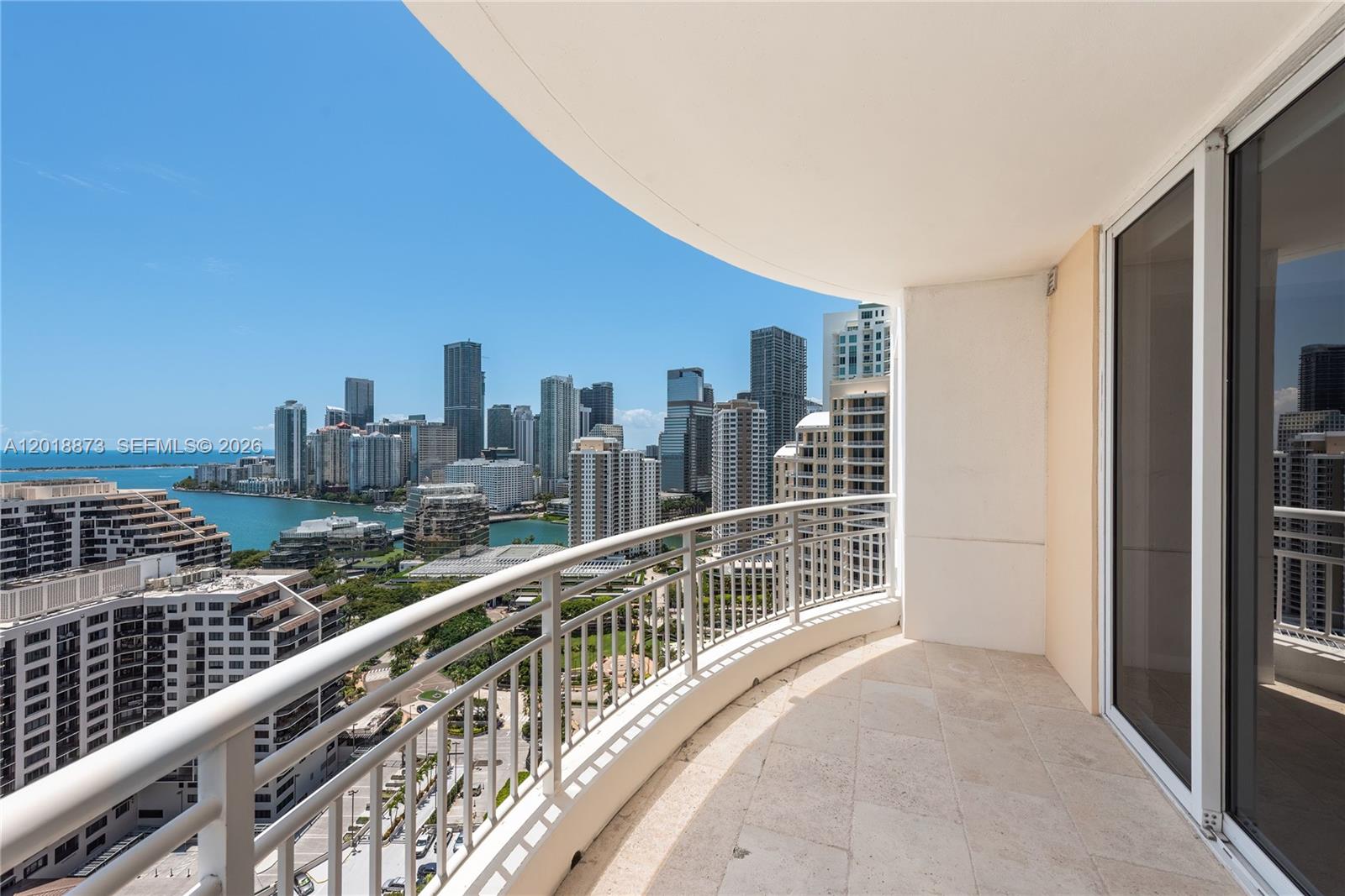 A high-rise balcony with a metal railing overlooks a city skyline and a bay — 848 Brickell Key Dr # 2703, Miami FL 33131, MIAMI, FL