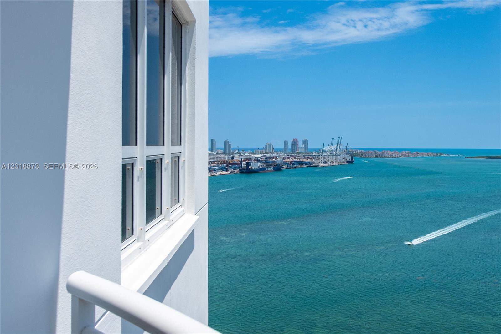 A high-rise balcony view overlooks a harbor with ships, cranes, and a distant city skyline — 848 Brickell Key Dr # 2703, Miami FL 33131, MIAMI, FL