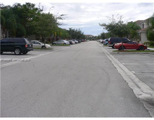 A paved parking lot lined with parked cars and palm trees between residential buildings — 1040 NE 42nd Pl, Homestead FL 33033, HOMESTEAD, FL