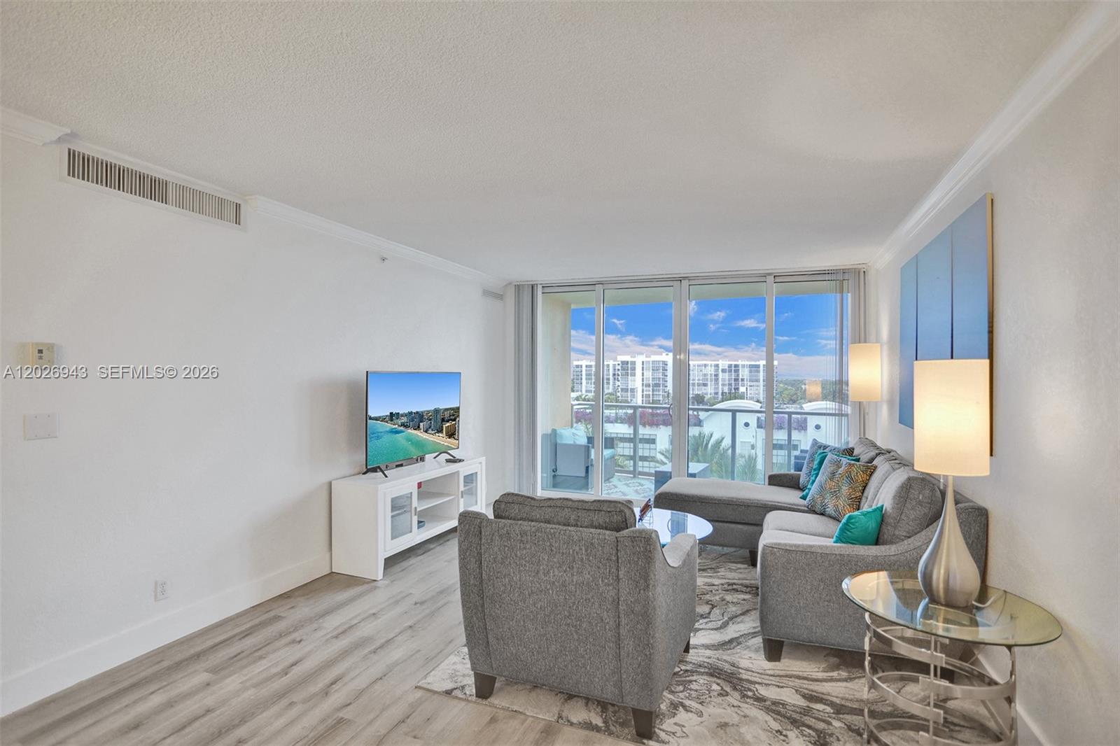 A living room features gray furniture, a white media console, and a balcony with views — 2501 S Ocean Dr, Hollywood FL 33019, HOLLYWOOD, FL