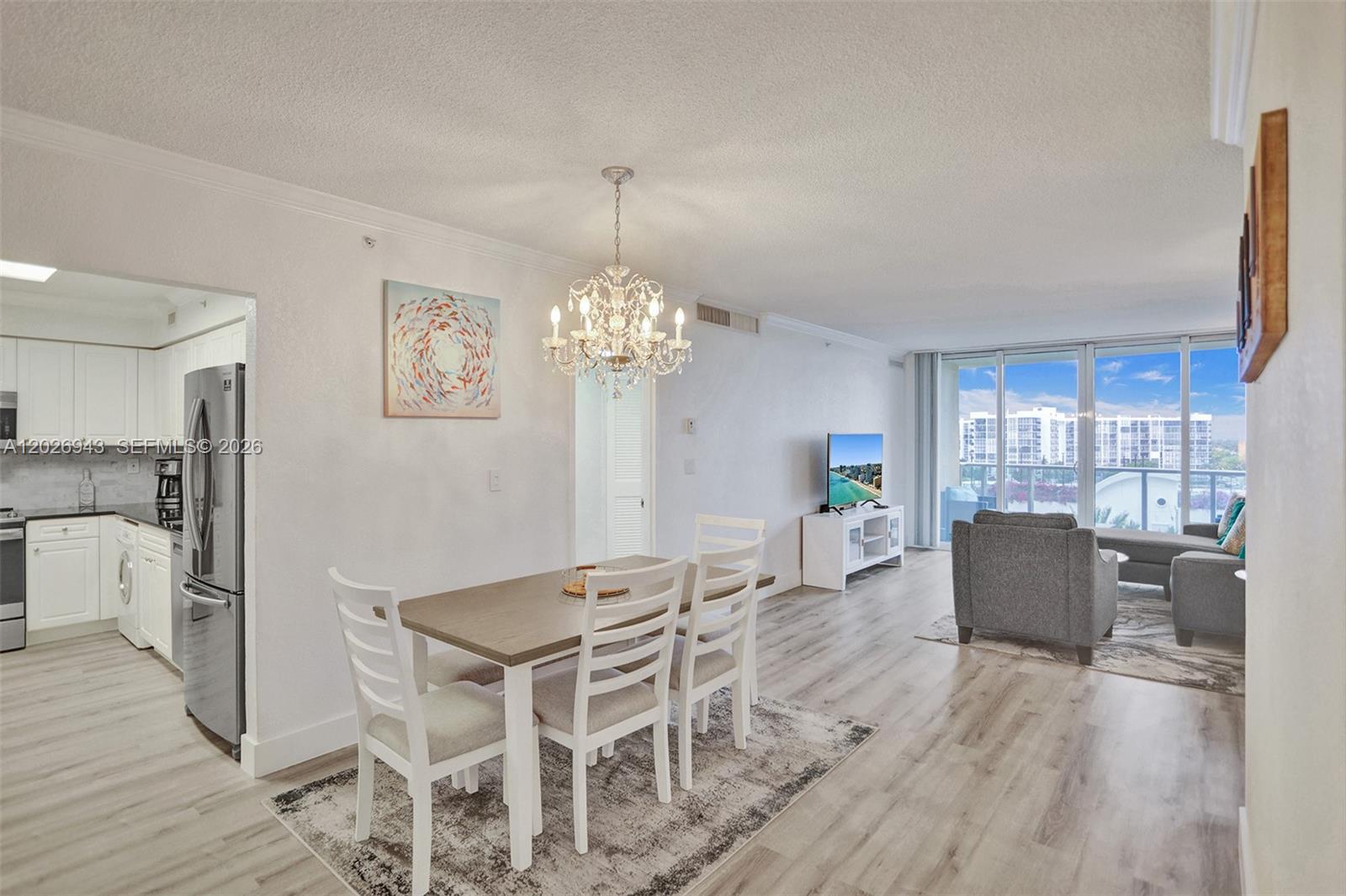 A dining area and living room feature light wood floors, white furniture, and a chandelier — 2501 S Ocean Dr, Hollywood FL 33019, HOLLYWOOD, FL