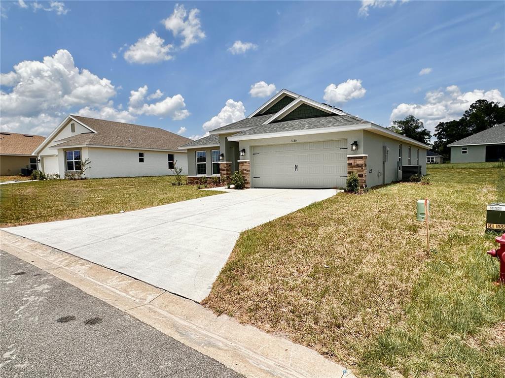 A single-story house with a light-colored exterior, a two-car garage, and a concrete driveway — 3135 NE 45TH AVENUE, OCALA, FL
