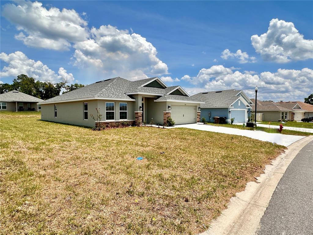 A single-story suburban house with a tan exterior, stone accents, and a gray shingled roof — 3135 NE 45TH AVENUE, OCALA, FL