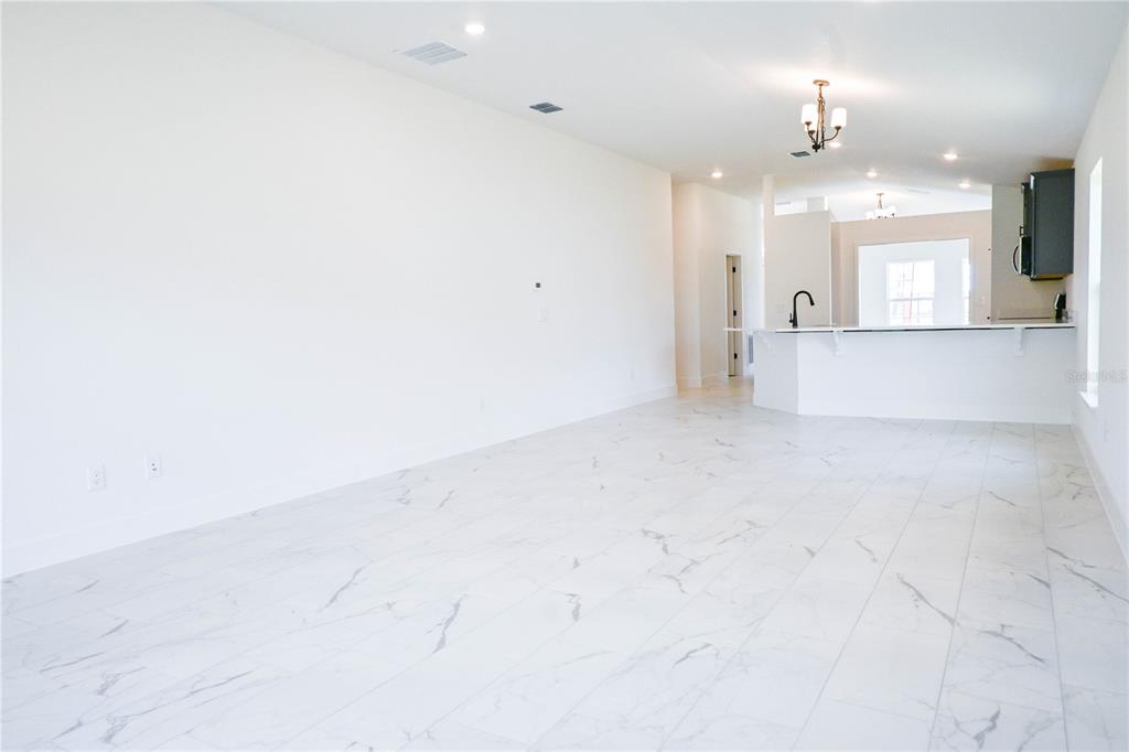 An open-concept living area features white marble-look tile flooring and a kitchen breakfast bar — 3135 NE 45TH AVENUE, OCALA, FL