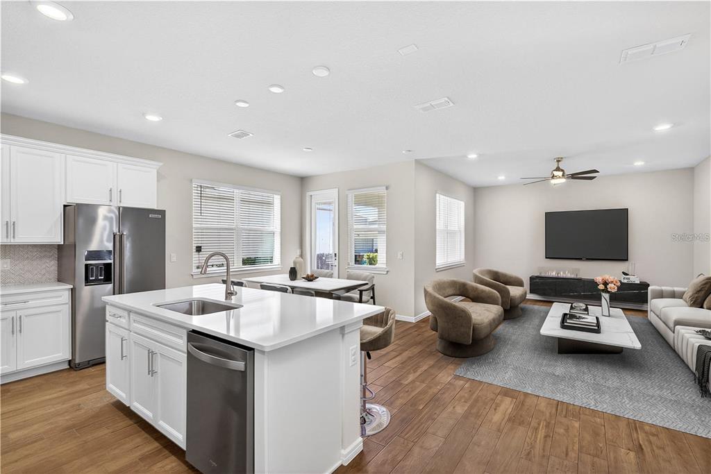 An open-concept kitchen and living area featuring white cabinetry, a center island, and wood flooring — 14250 LANIKAI BEACH DRIVE, ORLANDO, FL