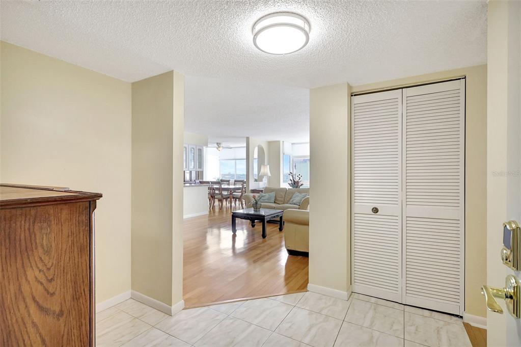An entryway with tiled floors leads into a living room with hardwood flooring and furniture — 660 ISLAND WAY UNIT 708, CLEARWATER BEACH, FL