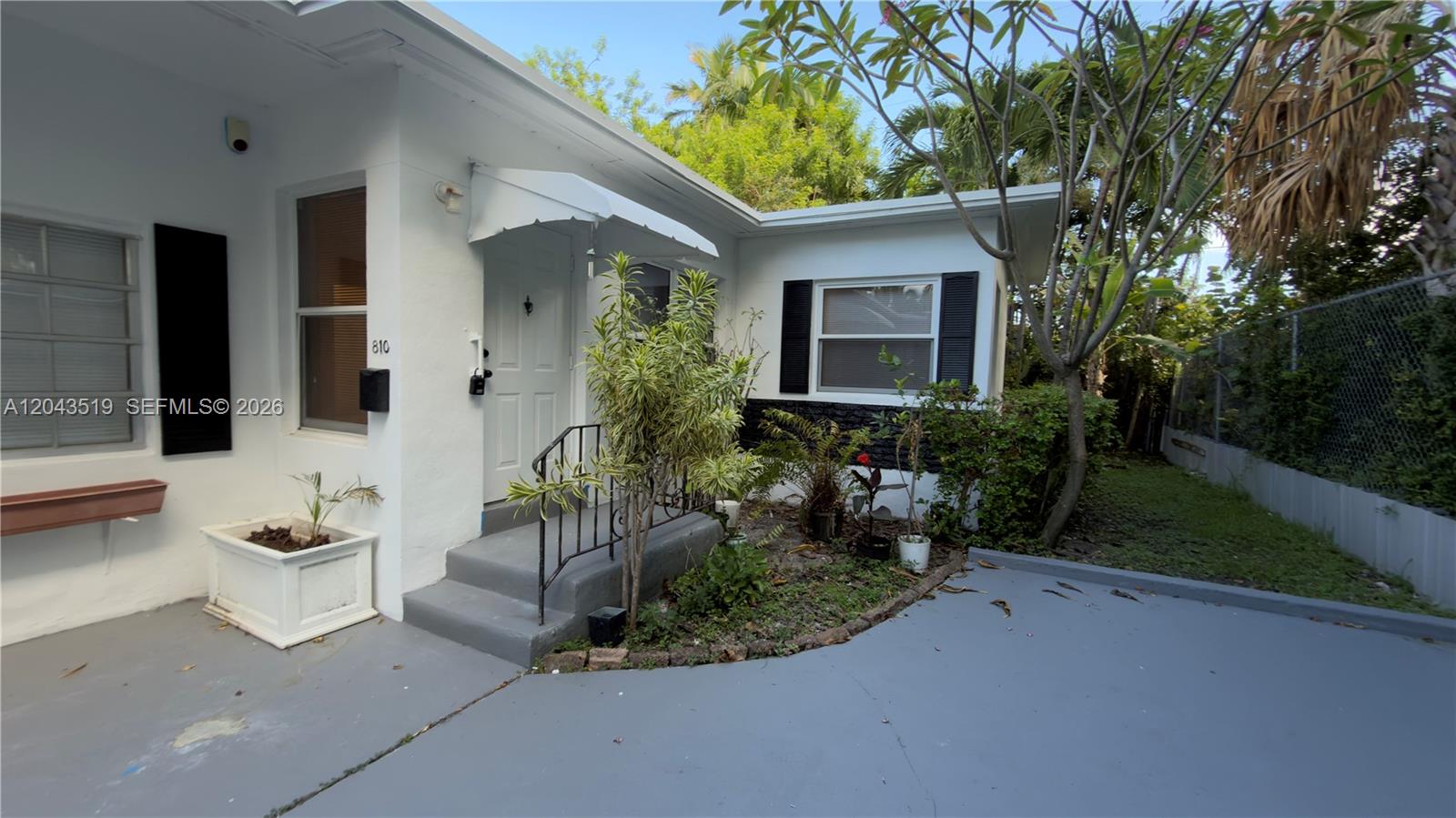 The exterior of a white house features a small front porch, landscaping, and a driveway — 808 84th St # 810, Miami Beach FL 33141, MIAMI BEACH, FL