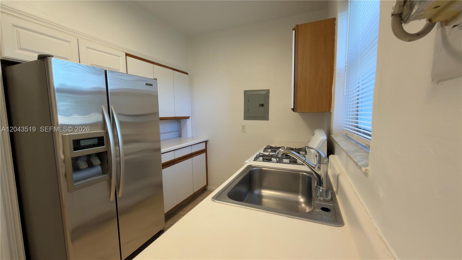 A galley kitchen features white cabinets, stainless steel appliances, and a single-basin sink — 808 84th St # 810, Miami Beach FL 33141, MIAMI BEACH, FL